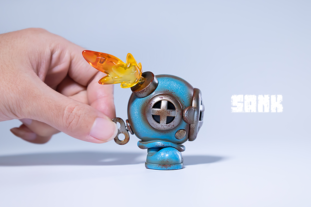 A hand holding Tiny Sank-Blues, a limited edition resin robot toy, available for preorder from Strangecat Toys, shipping in August 2024.