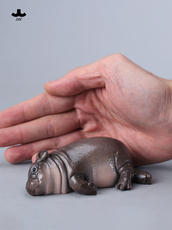 Hand holding JXK-Baby Hippopotamus Figurine-MooDeng 3, a small resin toy, part of a limited edition collection, available for preorder at Strangecat Toys.