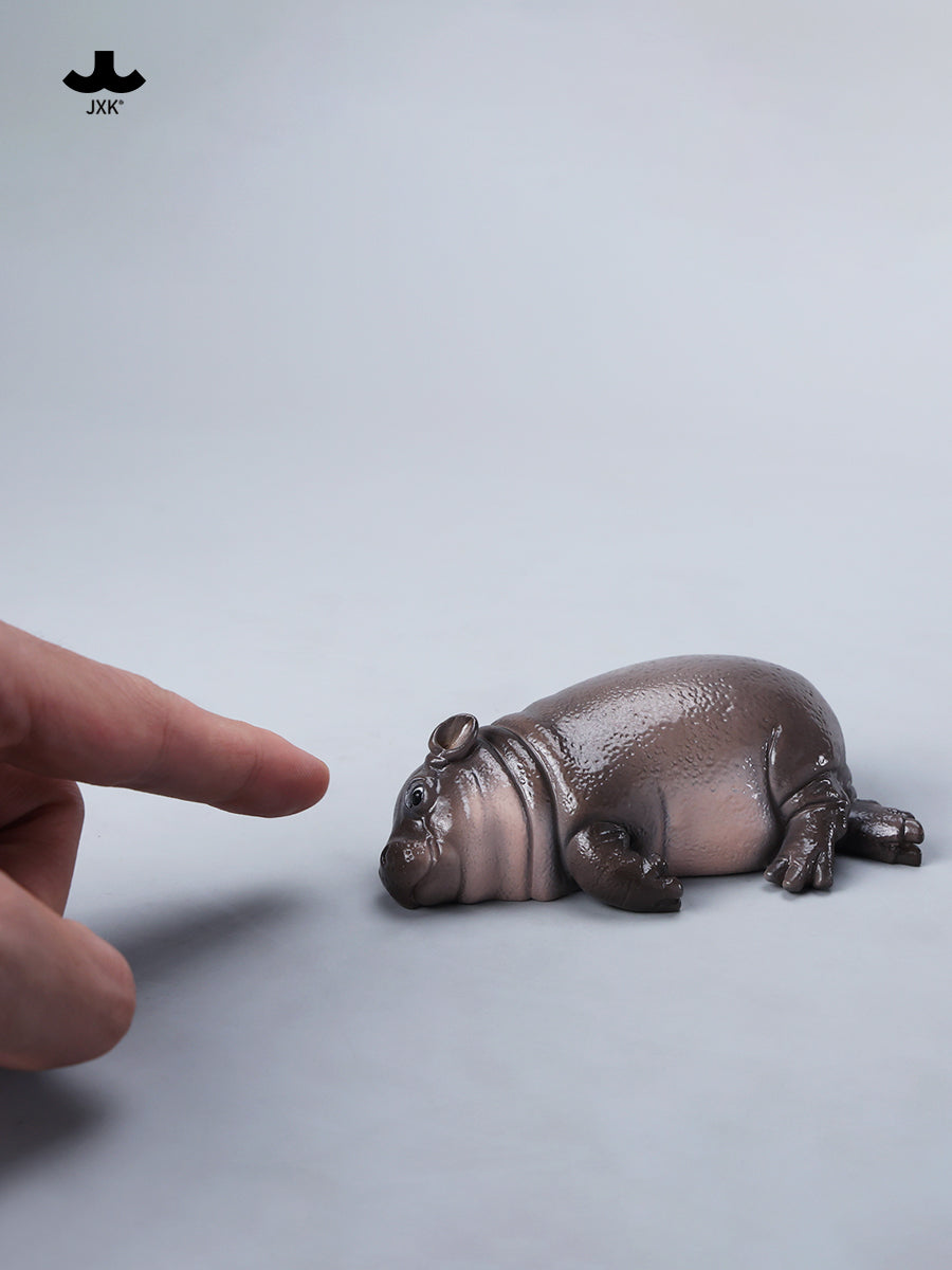 JXK-Baby Hippopotamus Figurine-MooDeng 3, a resin collectible, features a detailed hippo with a finger pointing at it, ideal for art toy enthusiasts.