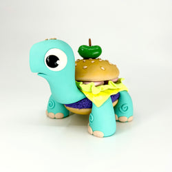 A toy turtle with a burger on top, part of Simon Says Macy & Friends - Turtlebuger - Pastel Goth Remix collection.