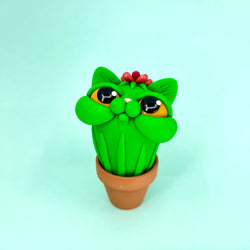 A green cat-shaped plant in a pot, toy, cartoon, animal figure.