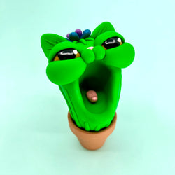 Polymer clay toy of Simon Says Macy & Friends - Purrickly Yowlbert, a green cactus cat head with mouth open and plant in pot.