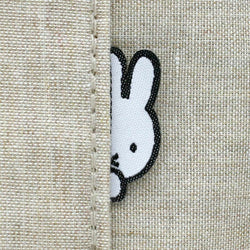 A close-up of a rabbit patch on fabric, part of Miffy - Siffler Shoulder Bag Beige from Strangecat Toys. Ideal for bags or pouches.