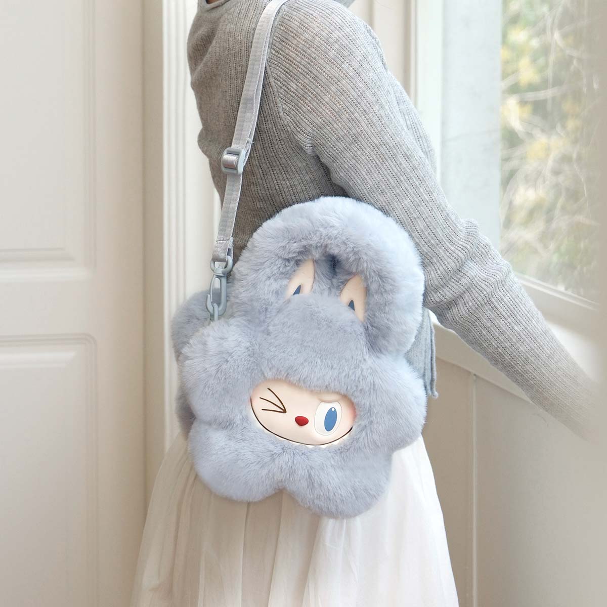 Woman holding THE MONSTERS Classic Series-Plush Flower Bag Blue, a bunny-shaped, furry bag available for preorder, made from polyester and silicone.