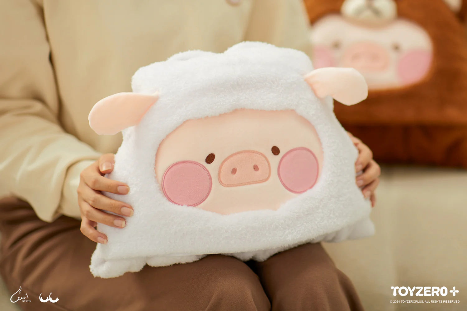 A person holds LuLu the Piggy Costume Series - Blanket with Hat, a cuddly stuffed animal. Size: 9.5 cm x 17.5 cm. Protects small cards and photos. Available on 7th May 2024.