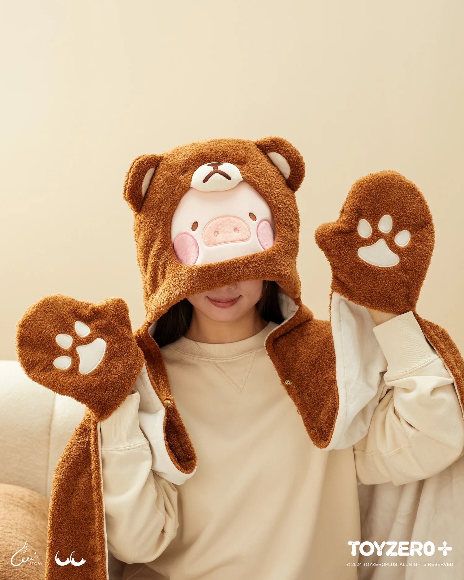 A woman wearing a bear garment and hat, holding a pig-themed photocard holder keyring from LuLu the Piggy Costume Series by Strangecat Toys.