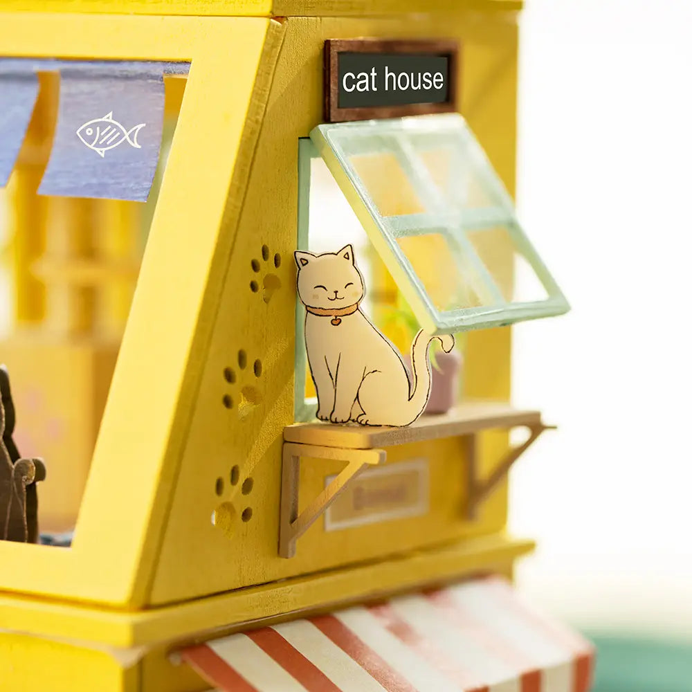 A DIY wooden dollhouse shaped like a cat, featuring three floors for cat activities like eating and playing. Dimensions: 11.4 x 7.7 x 2.8 in. From Strangecat Toys.