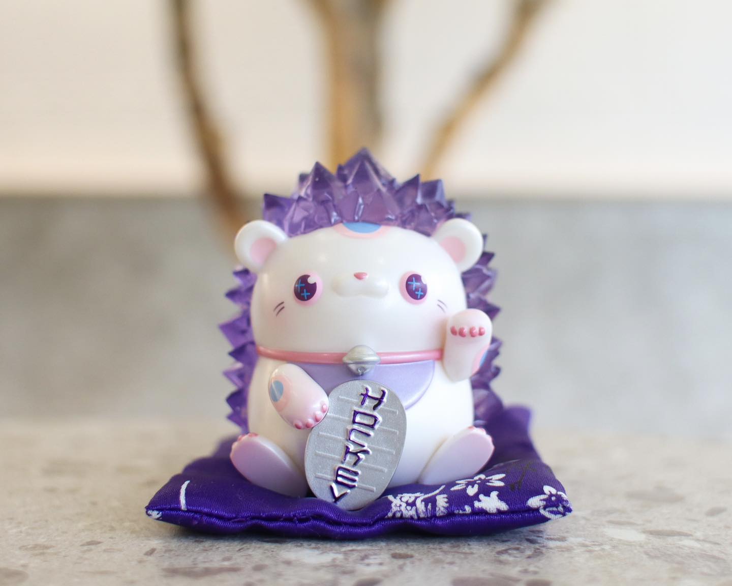 Maneki-Neko figurine, 10 cm tall, resin material, with purple Hogkey toy animal on a pillow.