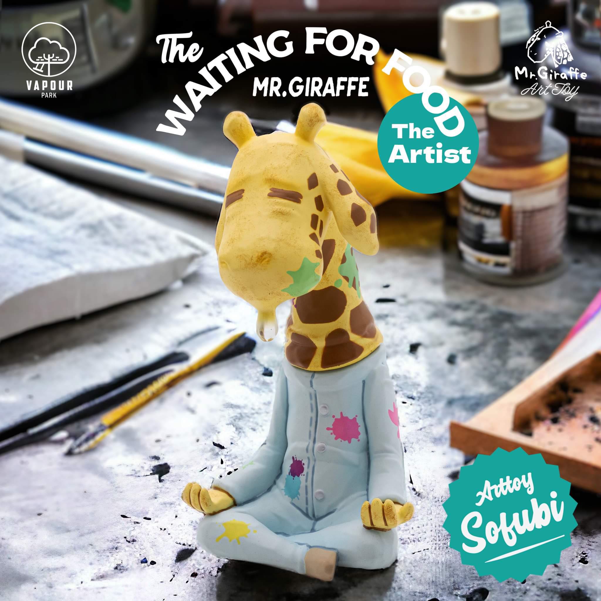 15cm tall vinyl toy giraffe sculpture, MR. GIRAFFE - The Artist, sitting on a table wearing pants and a shirt.