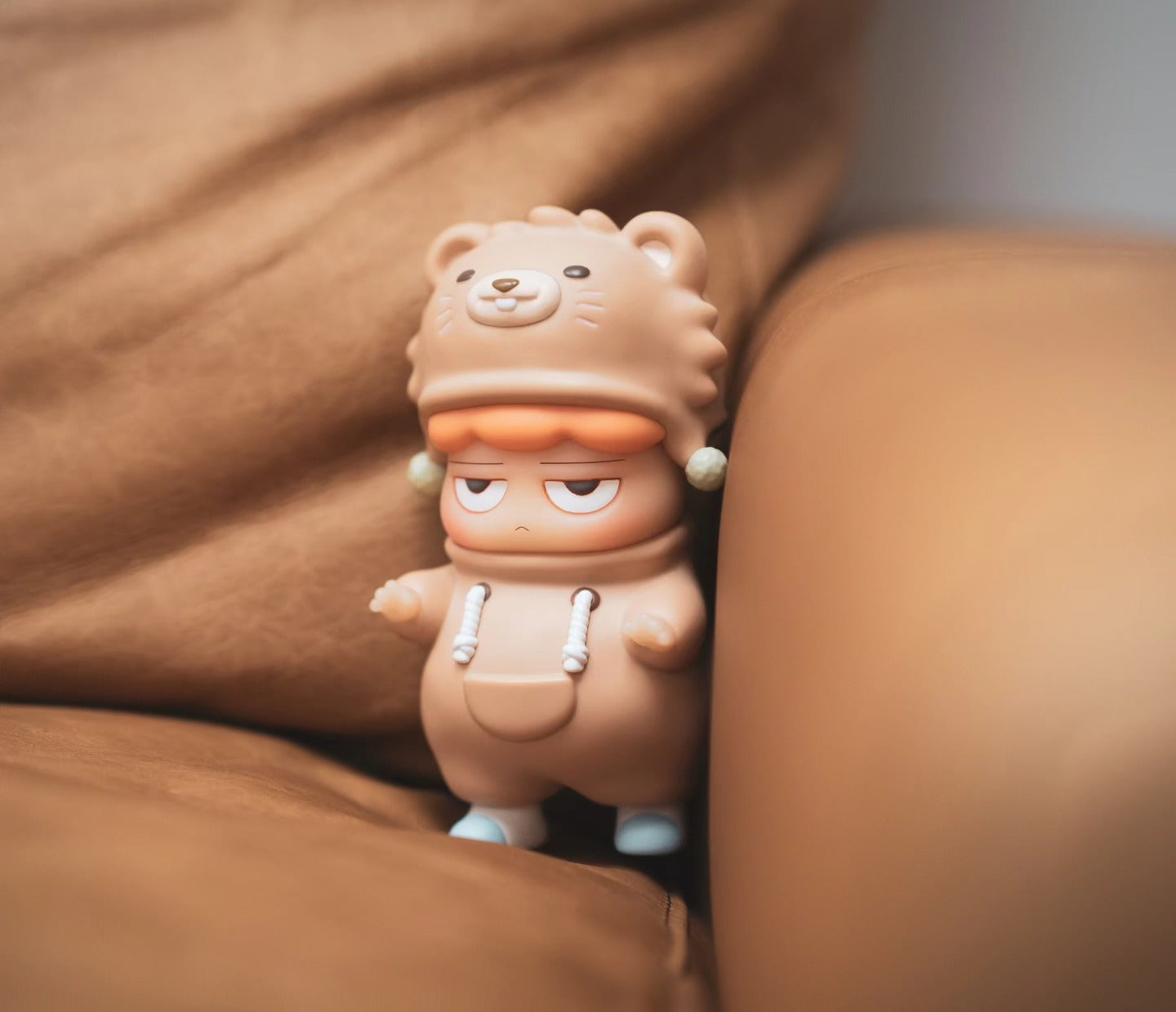 A vinyl POH Bear toy figurine by Vin on a couch, embodying Strangecat Toys' blind box and art toy store essence.