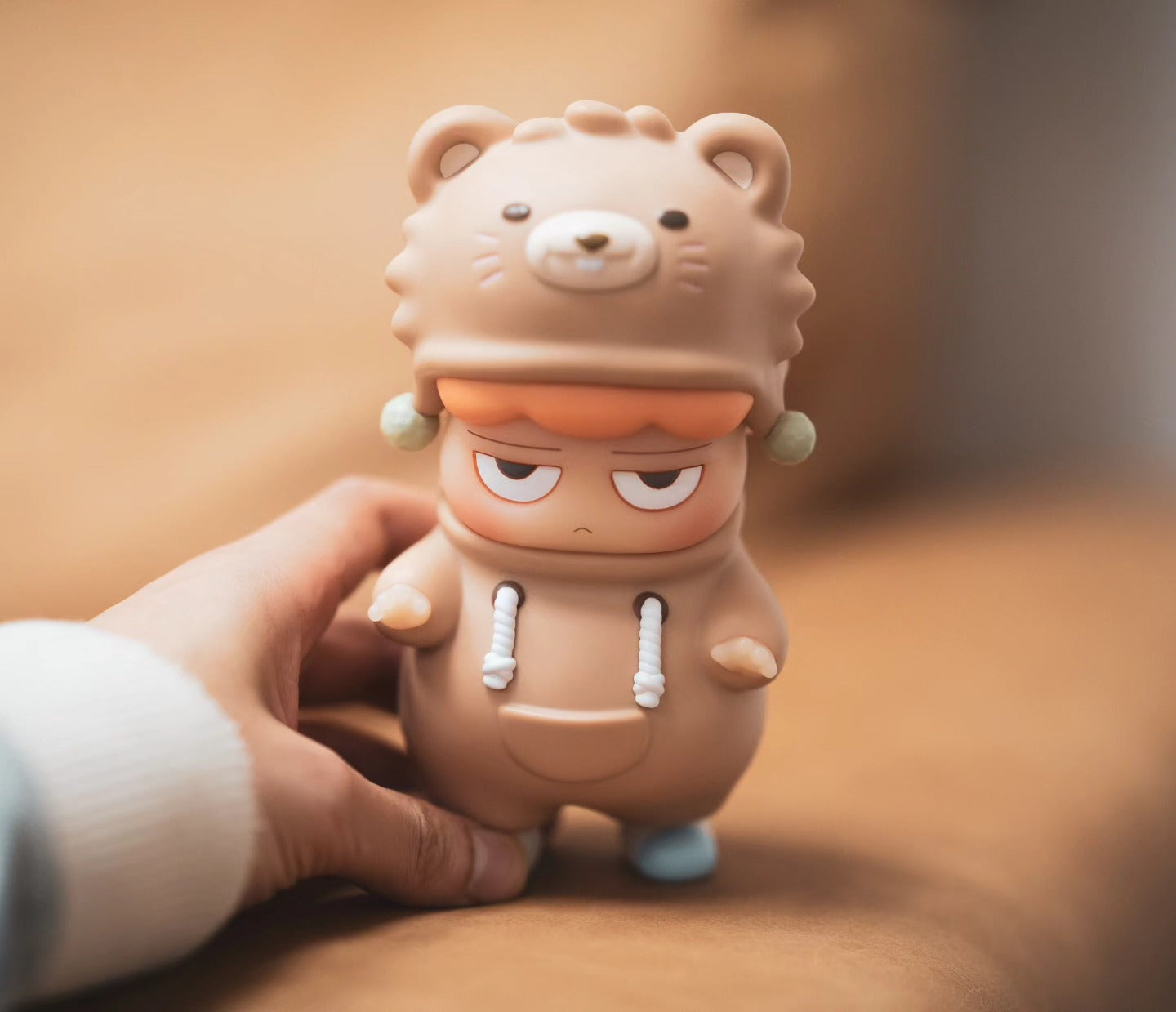 A hand holds a cartoon figurine, a toy from Strangecat Toys. Preorder - Ships Late May 2024. POH Bear by Vin.