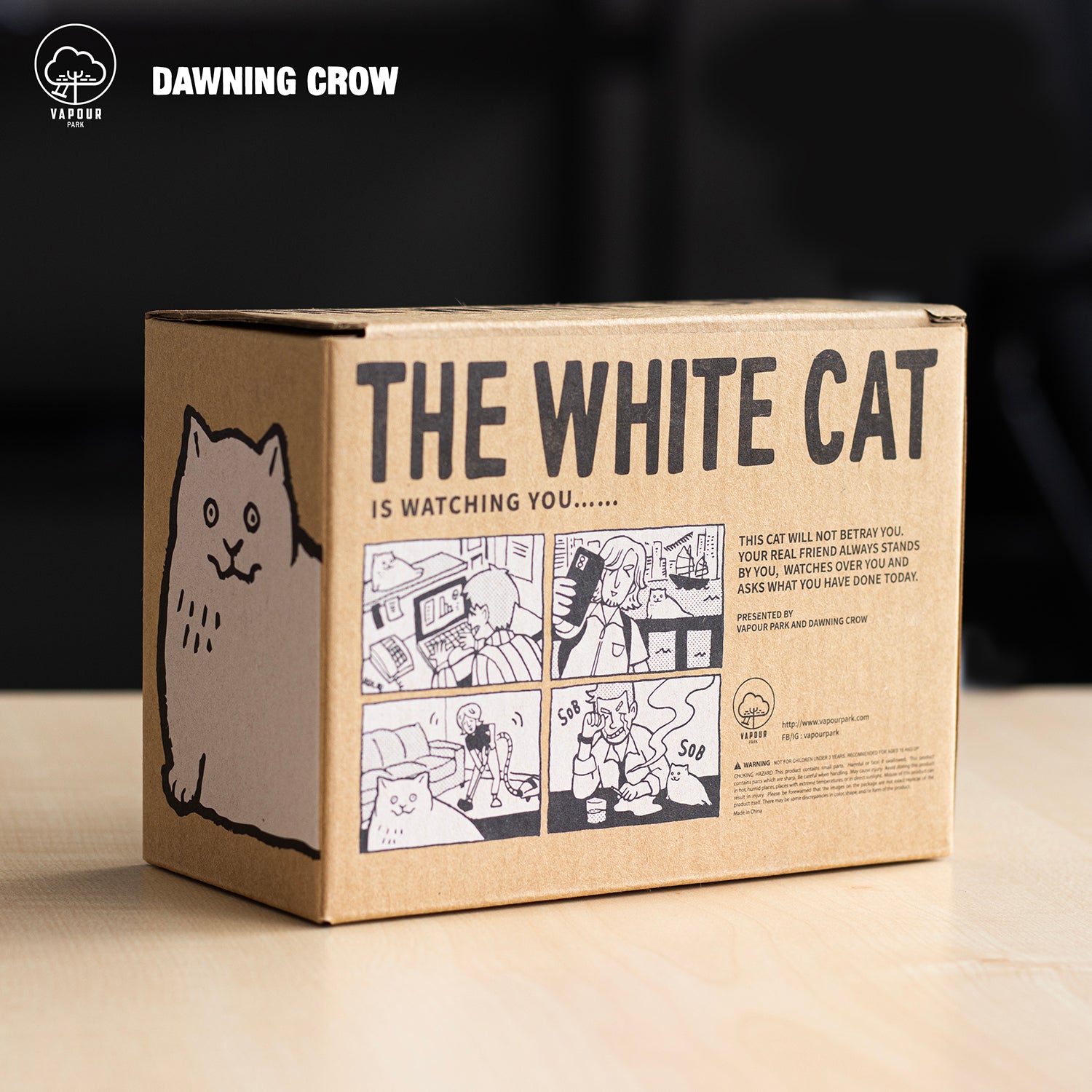 Preorder THE WHITE CAT by Dawning Crow vinyl figure on a box with a cat, a comic strip, and a man using a laptop. Ships Aug 2024.