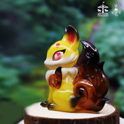 A small yellow amber Koma itsune figurine by Genkosha, depicting a phantom fox angel with snow-white hair and silver-purple flames, guarding villagers from a snowstorm.