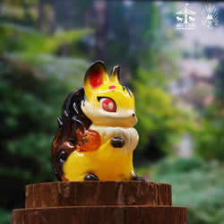 A small yellow and black fox figurine on a tree stump, part of the Koma itsune - Yellow Amber collection by Genkosha at Strangecat Toys.