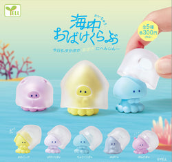 A hand holding a plastic toy from Ale Undersea Ghost Club Gatcha Series - Preorder, with a pink round toy, a yellow toy with a face, and more.