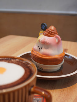 Croissant Han Han toy and cup of coffee on plate with bear face cup and paw print.