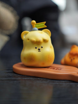 Yellow bear-shaped resin toy, titled Hanhan bread by Unknown Island, placed on a wooden surface.