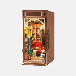 A miniature book nook kit featuring a red chair, books, and a cozy atmosphere. Robotime-Rolife Bookstore experience with realistic details for adults. Dimensions: 9 x 3 x 12 in.