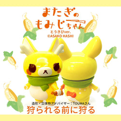 Momiji-chan Corn Ver. by Asako Hashi, a cute toy animal figure with a green scarf and unique features, part of a whimsical character's journey in Hokkaido.