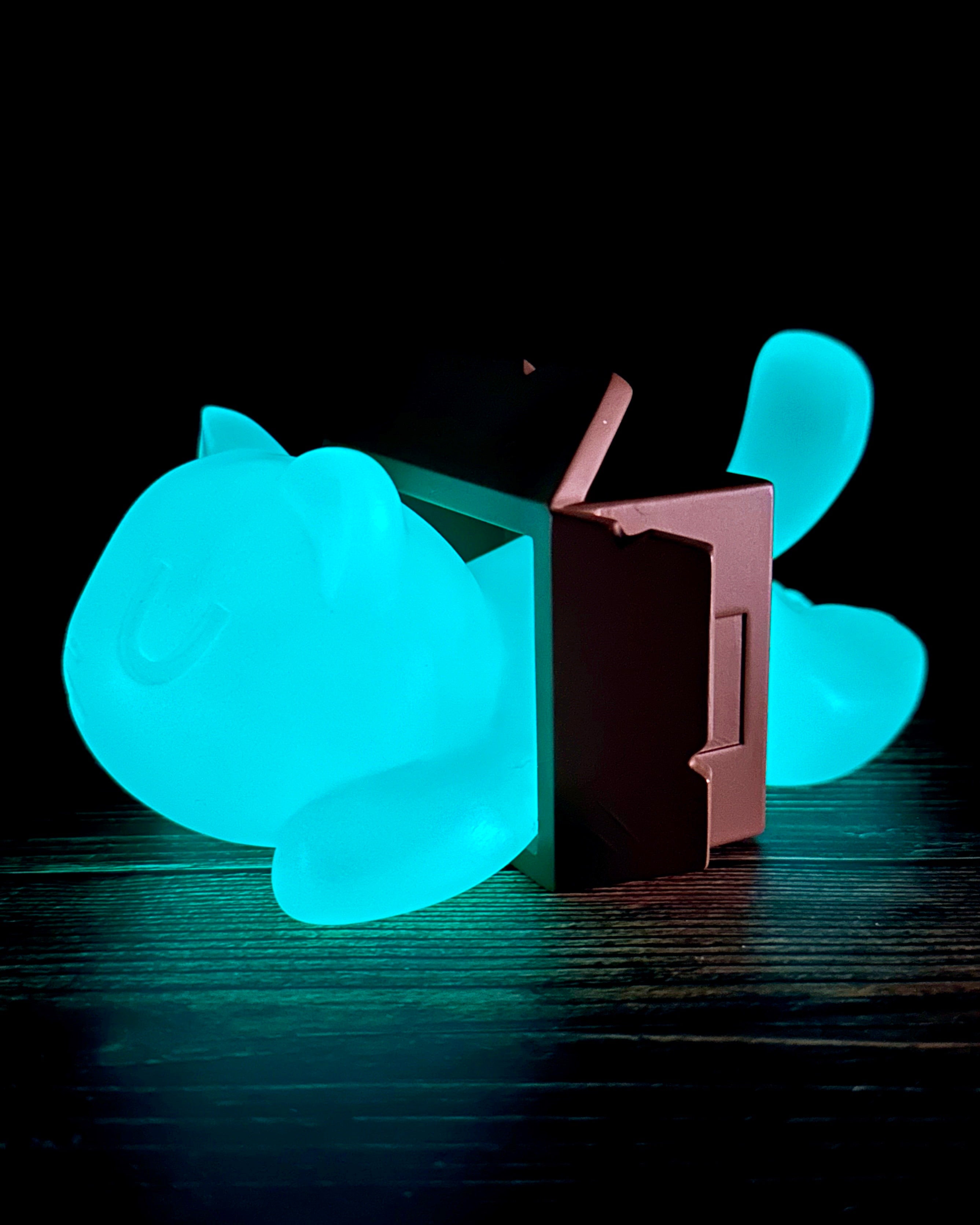 Little Mort by Saint Monday, a 5-inch glowing resin toy cat, displayed on a table, features three magnetized parts. Preorder available for June 2025.