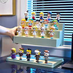 A hand holds a display case of small action figures, including toy figurines of a person, cartoon characters, and girls. Preorder for Mini Figure Display Case. Stackable design in two sizes.