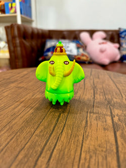 A blind box art toy: Mammotha - Half Yellow Banana by YASU. Sofubi toy, 7.6cm, featuring a green elephant with a hat.