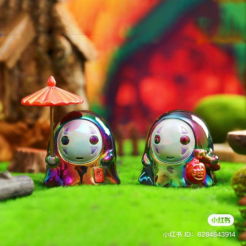 Two small No Face Man Blind Box Series figurines on grass, featuring distinctive round faces, part of a collectible set with regular and secret designs.