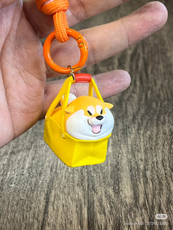 Shiba Inu GouQi keychain from Puppy Crossing Blind Box Series, featuring a dog in a yellow bag. Preorder for late April 2025 release.