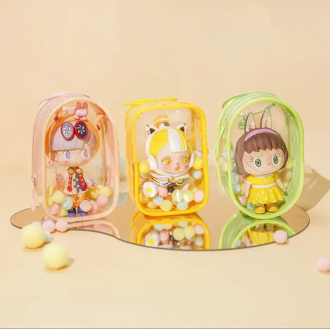 Toy Pochette Keychain: A set of small, colorful plastic dolls in clear cases with keyring attachments, featuring bells, rings, and hairballs for display.