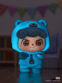 Be Your Q Baby Blind Box Series toy in a blue bear garment with cartoon face and zipper details. Preorder available, ships Aug 2024.