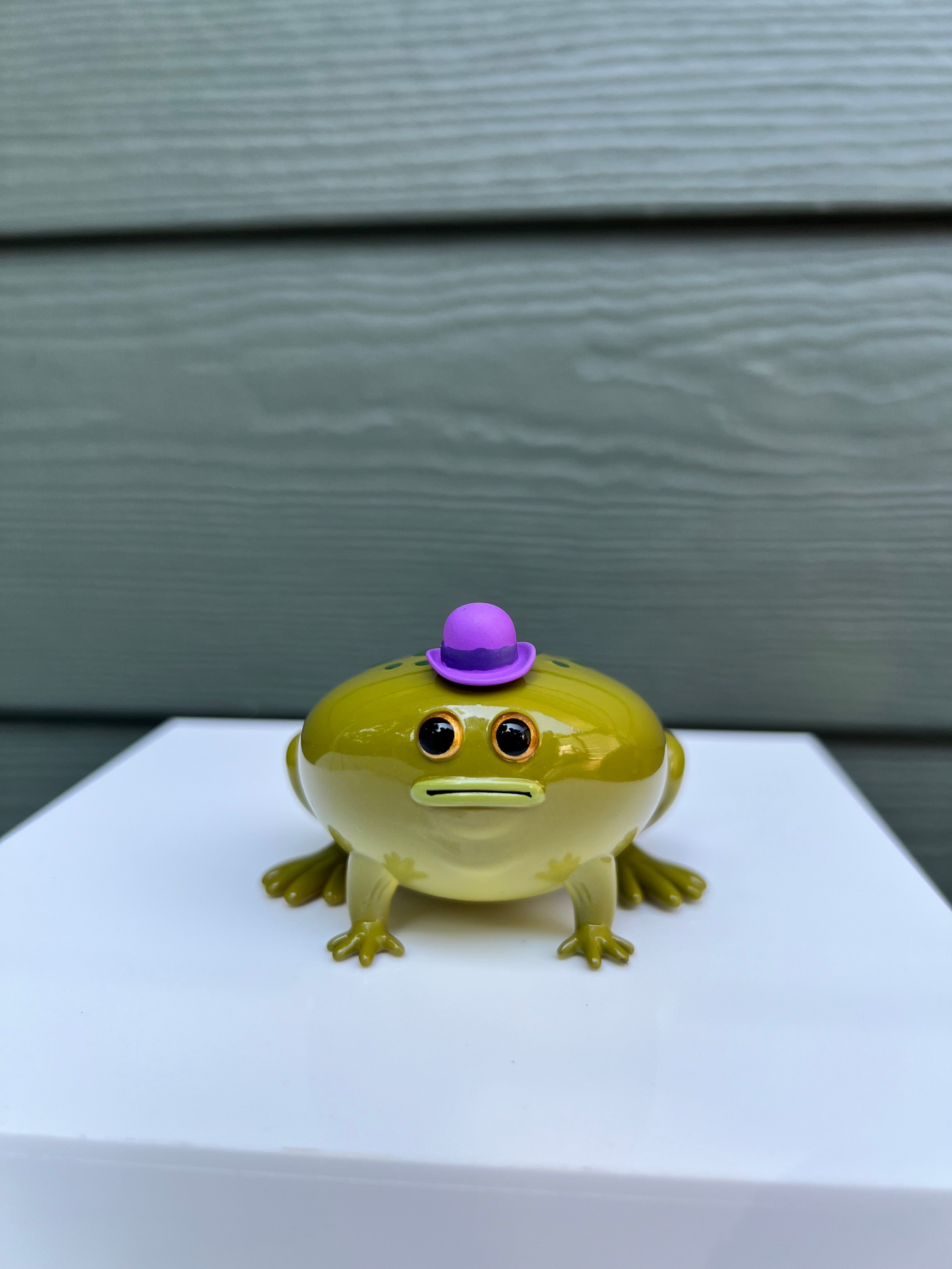 Frod by Sad Salesman: A 2.5” x 3” soft vinyl toy frog wearing a purple hat. Limited edition of 100 pieces.