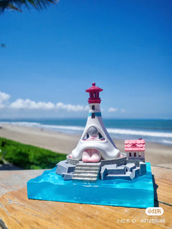 Preorder Notte Lighthouse by 1001Moons: a small toy lighthouse on a beach, with island base and lamp set. From Strangecat Toys.