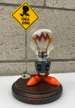 A limited edition Grim Ideas - Wattson by Riser resin figure, 5.5 tall, 9 with base. Depicts a light bulb character with legs and a crown.