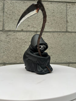 A limited edition 7 tall resin statue titled Grim Ideas - The Lone Reaper by Riser. Features a skeleton figure holding a scythe. From Strangecat Toys.