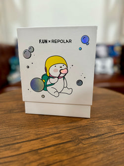 A white PVC card and box featuring a cartoon baby character, a circular object, and a blue circle with black lines. Limited edition Repolar 150% blow bubbles product from Strangecat Toys.