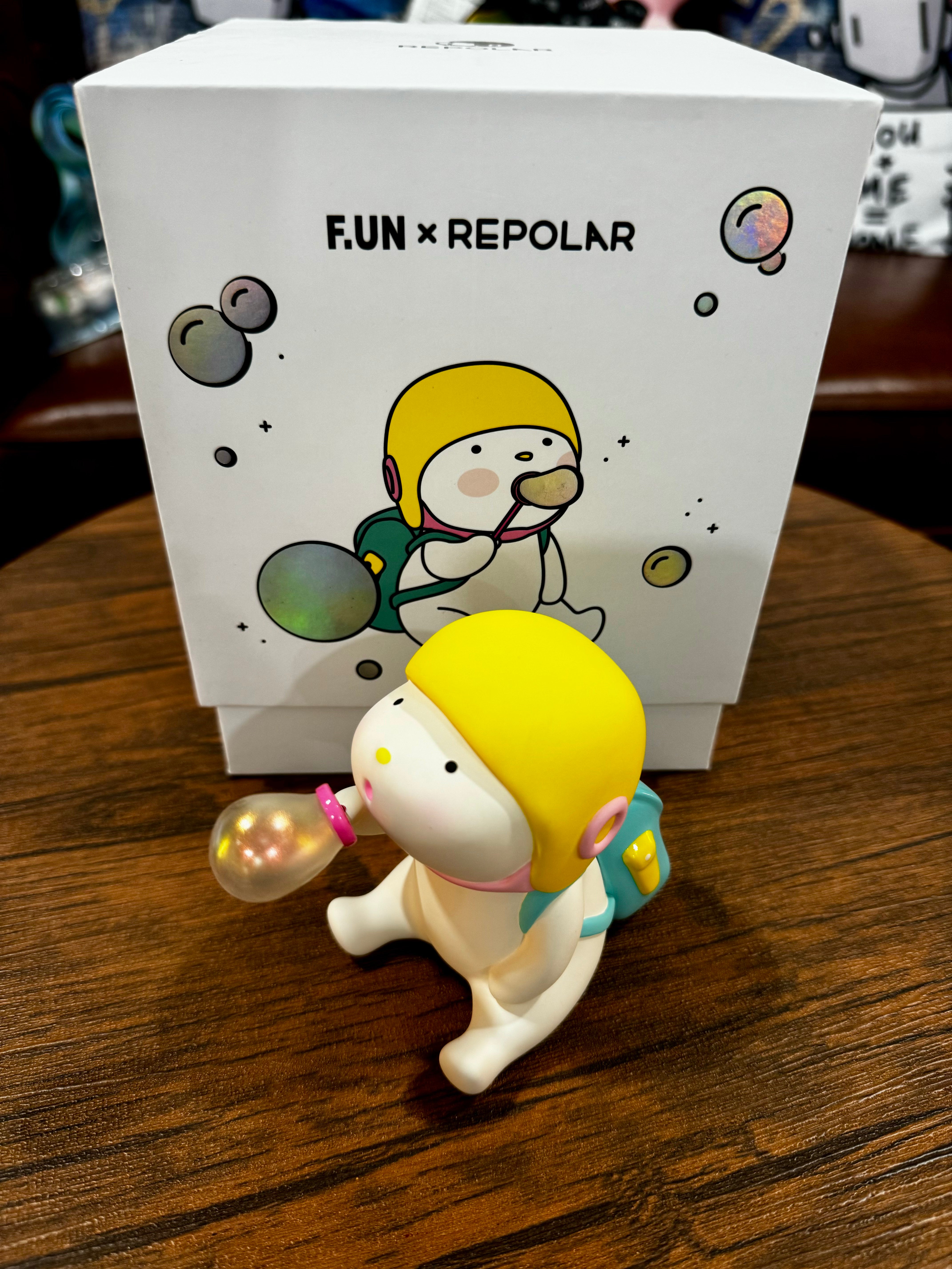 A toy figurine of Repolar 150% blow bubbles, PVC material, 6-inch size, limited to 1001pcs, with a cartoon character box and bubble detail, on a table.