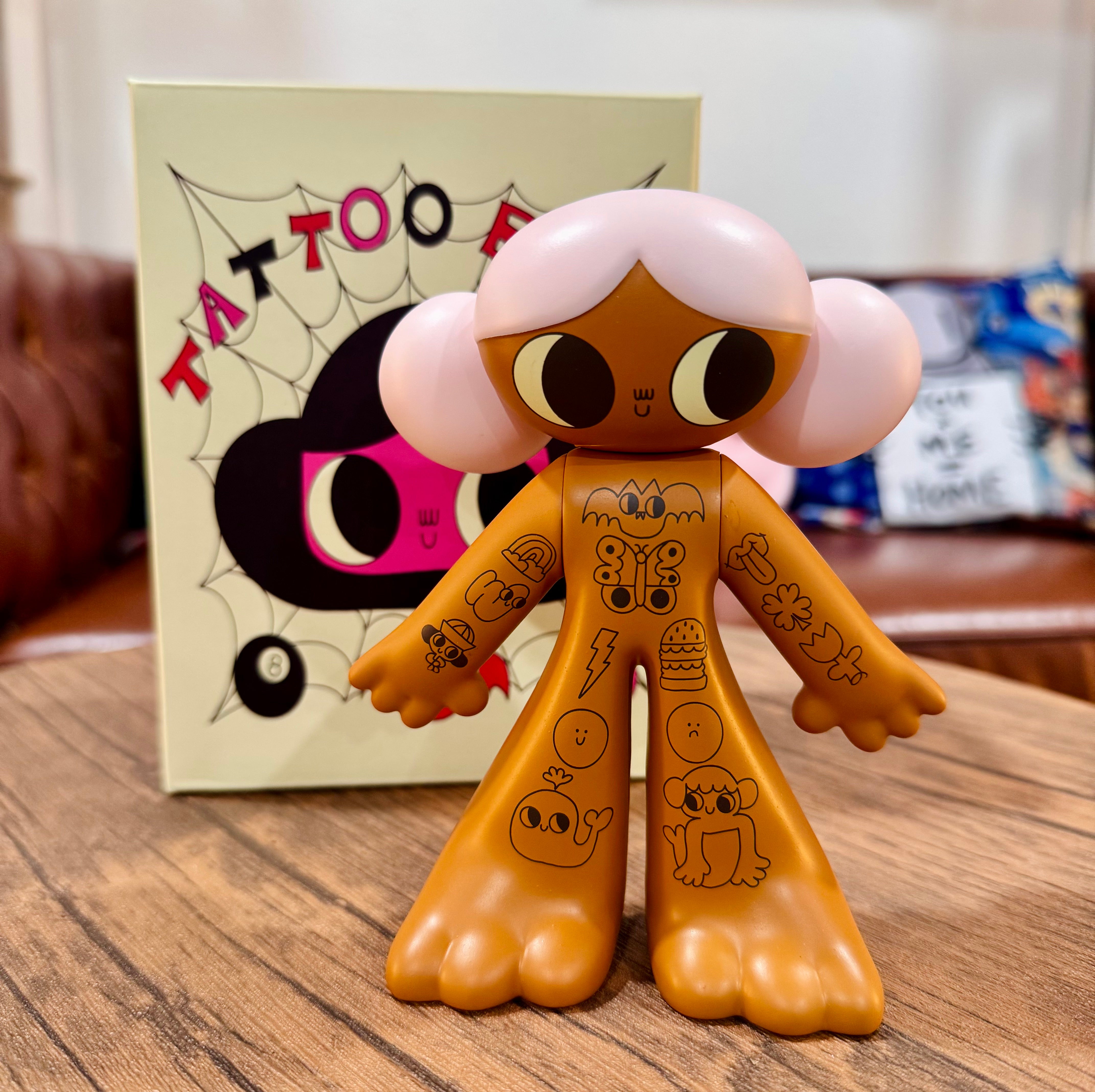 Tattoo Girl - Louise by Burger Babie, a limited edition 5 vinyl toy figurine, displayed on a table with intricate designs, in front of a book.