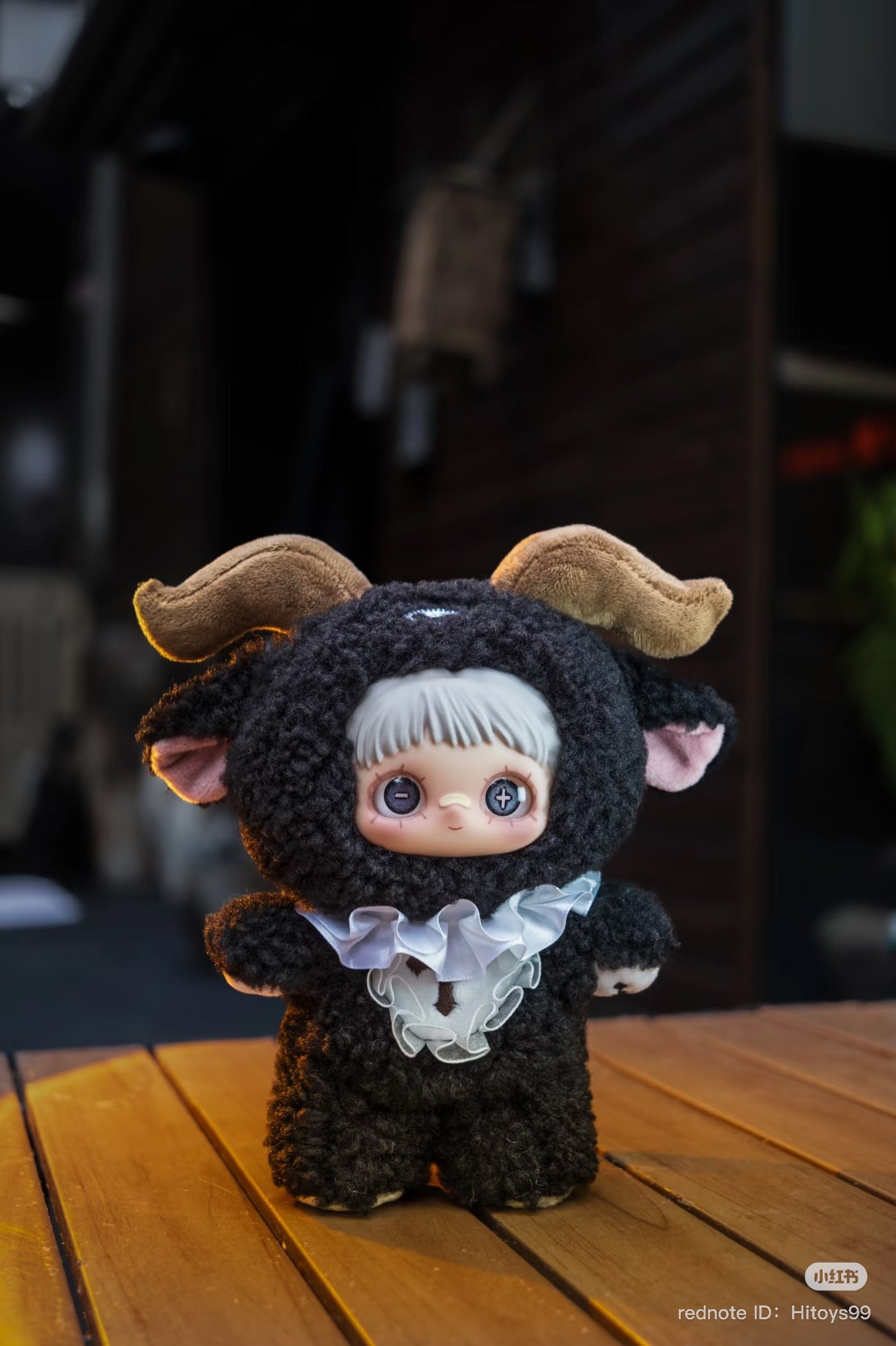 Maymei Dark Forest Plush Blind Box Series features a stuffed toy in a garment, displayed on a wooden surface, part of Strangecat Toys' art collection.