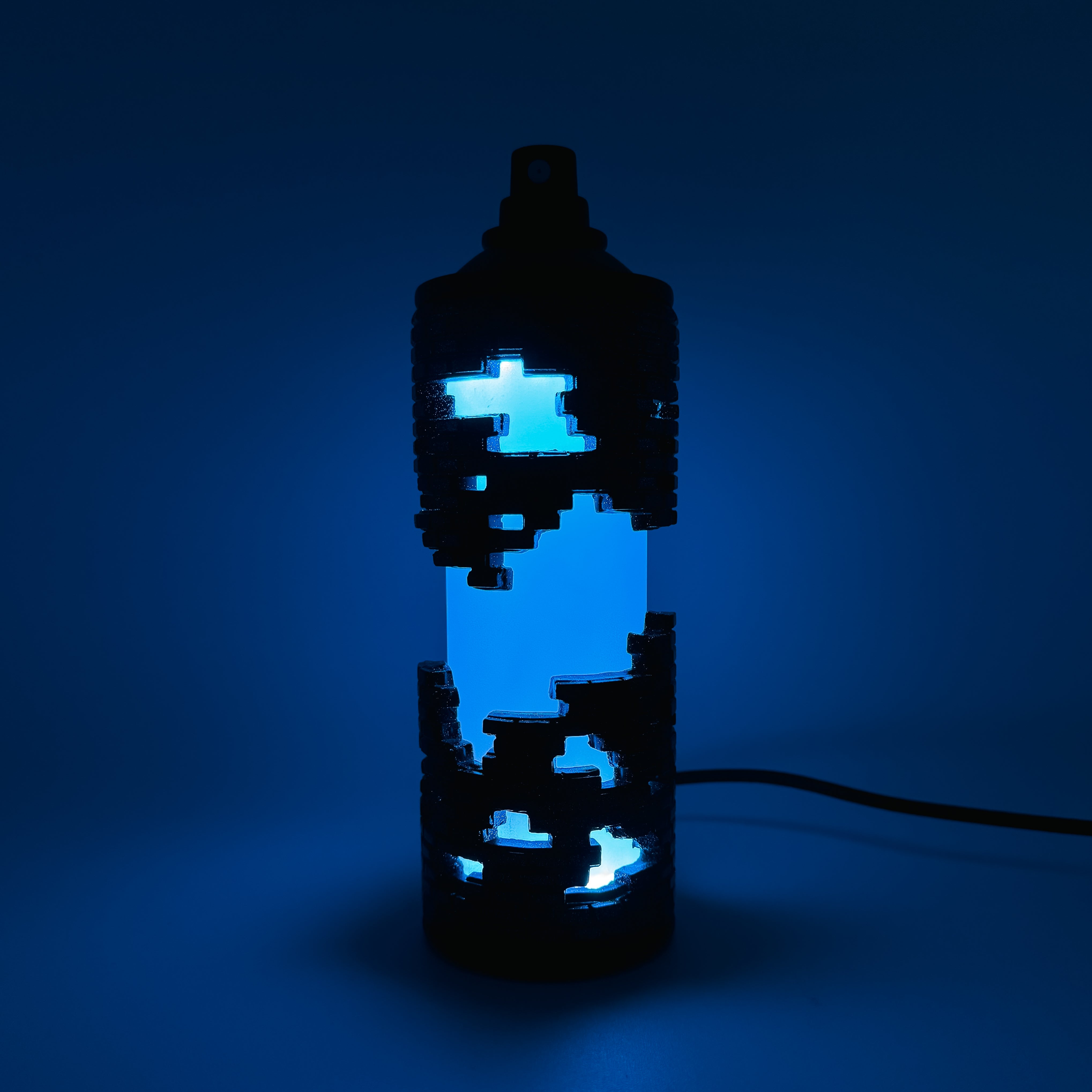 Hello World - BRIX NEBULA CAN by JFO, featuring a blue light within a sleek black container, includes a power cable. Ships 28 days post-show opening.