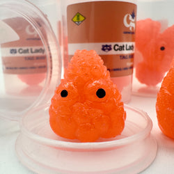 Hello World - THC BUDZ by JFO, an orange slime toy with black eyes in a plastic container, part of Micro Sets of 3 collection.