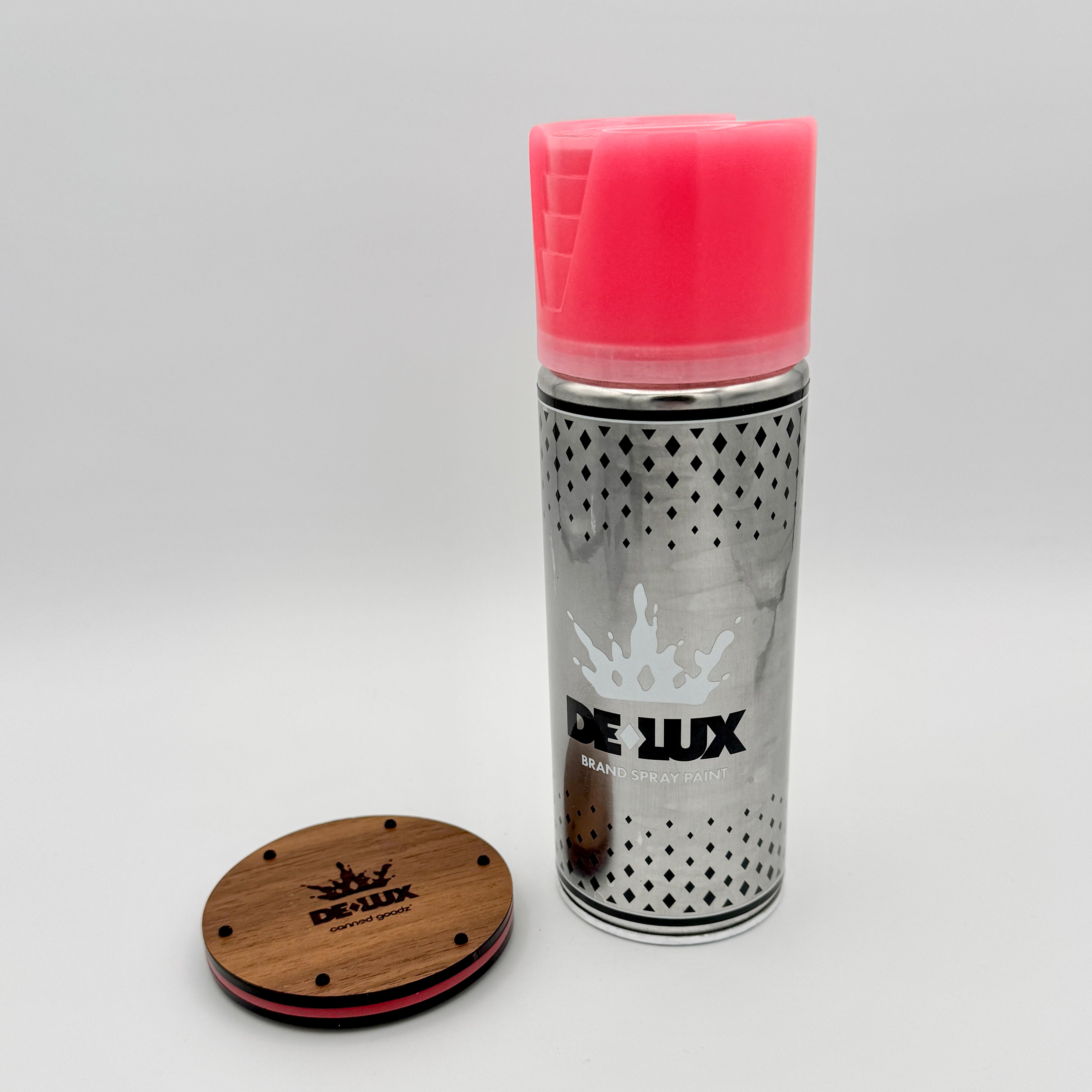 Hello World - DE-LUX CAN by JFO, featuring a spray can with a red top and a round wooden coaster displaying a logo.