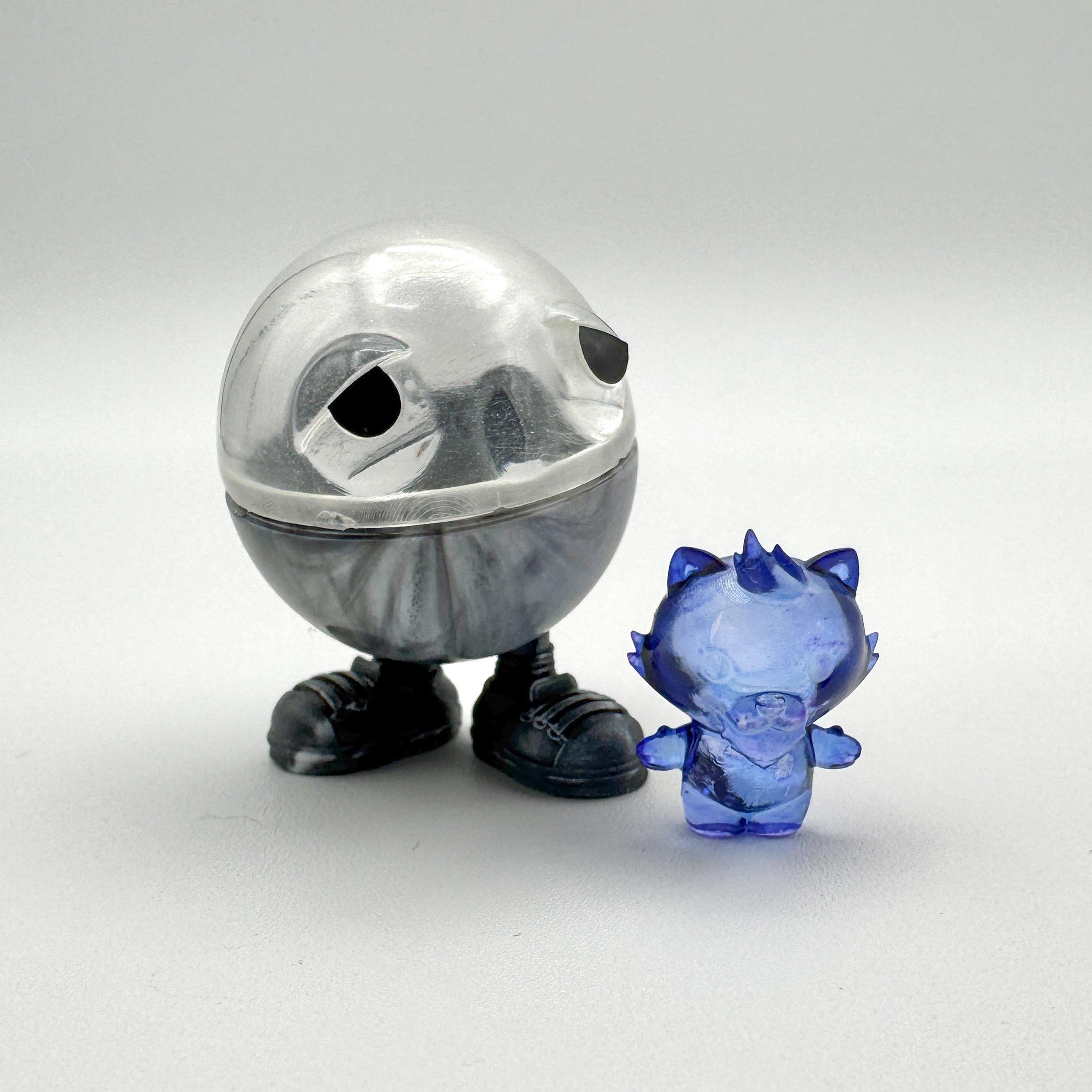 Hello World - MR. CAPS + GRANDPA by JFO: A round-bodied plastic toy, resembling a piggy bank, includes a power cable and base.