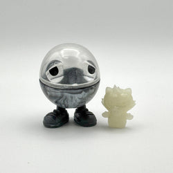 Hello World - MR. CAPS + GRANDPA by JFO, a plastic toy with a face and legs, includes a power cable and base.