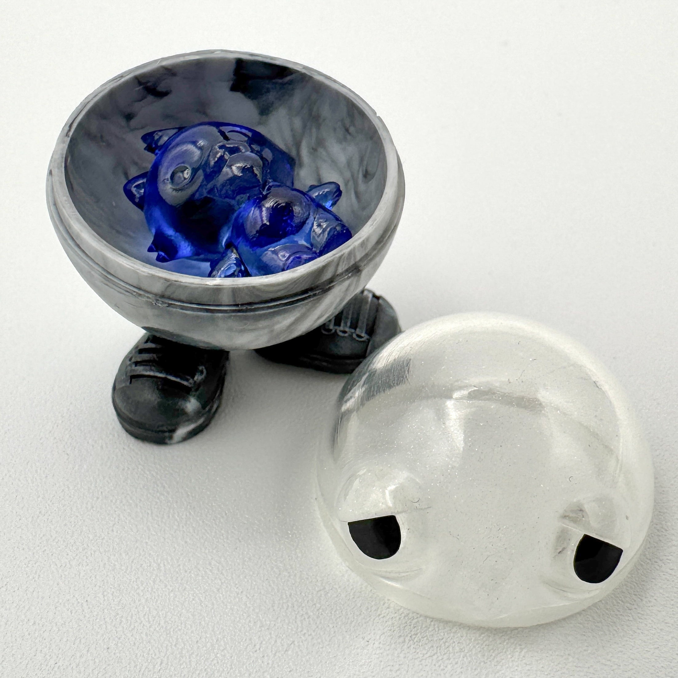 Hello World - MR. CAPS + GRANDPA by JFO, a blue glass art toy featuring distinct eyes, set in a bowl. Includes power cable and base.