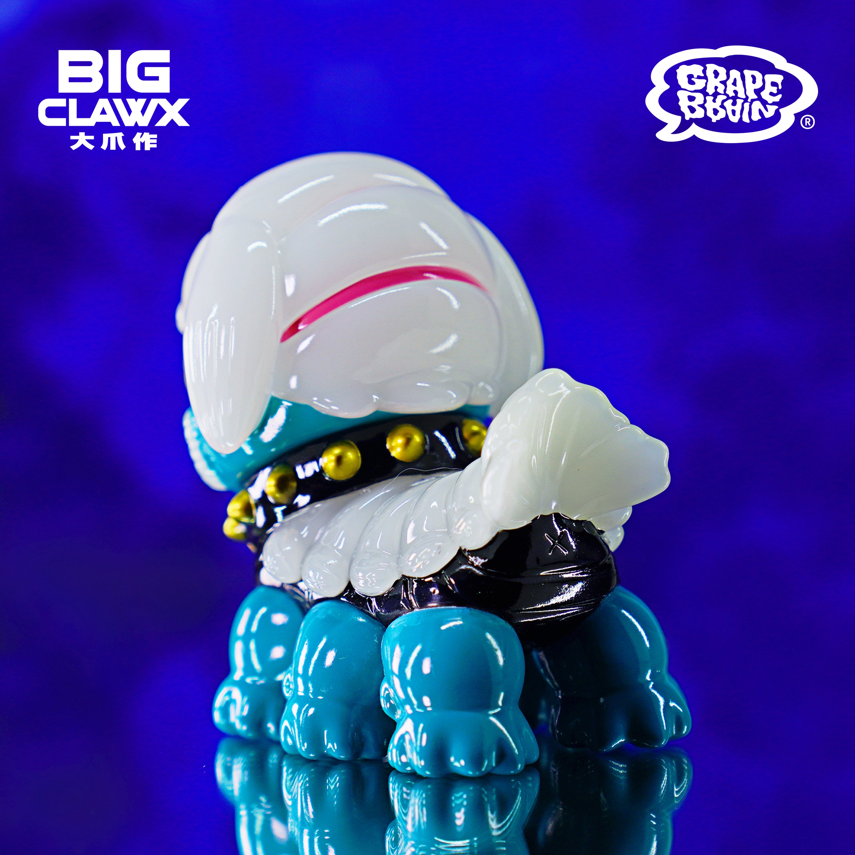 A close-up of a toy by BigClaw x Grape Brain, featuring a blue and white design, 9cm soft vinyl.