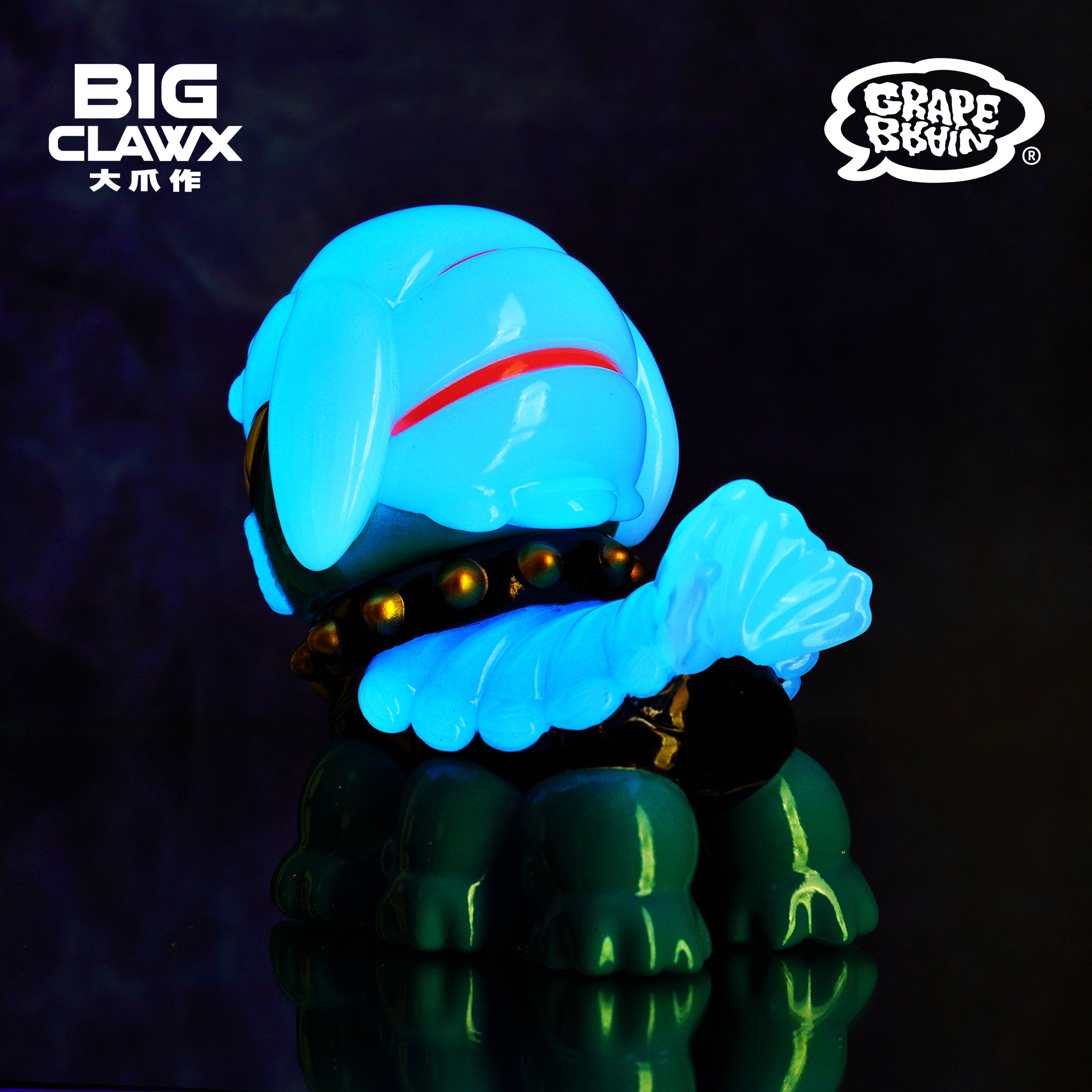 A soft vinyl toy featuring a cartoon character with text details, part of the Cola - GID Blue by BigClaw x Grape Brain collection.