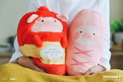 A person holding LuLu the Piggy sausage pillow, a stuffed animal with a cartoon pig face.