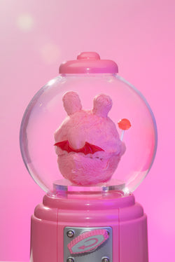 Sweet Death by Shinwoo: A whimsical pink stuffed animal with wings, encased in a resin snow globe, holding a lollipop.