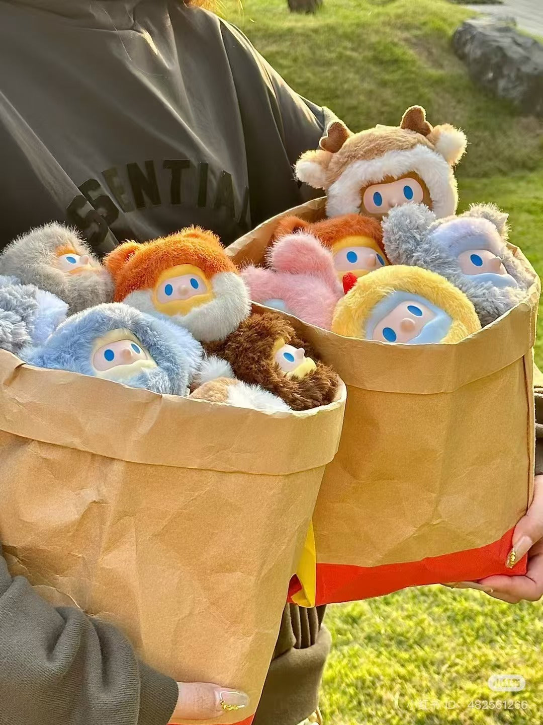 Person holding two brown bags containing Farmer Bob Tiny Monster Plush Heads, showcasing small, horned stuffed animals.