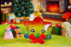 Weee Tree Rainbow by Kiwi, a glass animal with a red bow and a colorful toy with a red bow, a blurry stuffed animal and a penguin on a green surface.